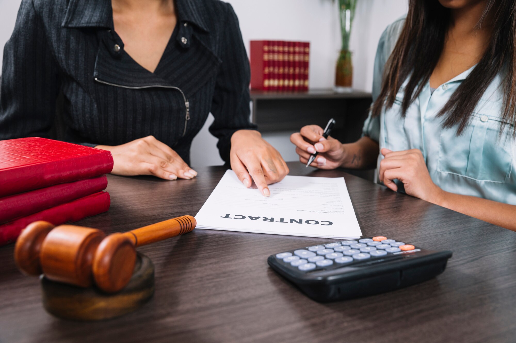 black woman pointing document near lady with pen table with calculator gavel 23 2148042590